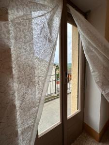 una puerta abierta con cortinas y un balcón en Casa Vacanze ''La Torre'' en Cascia