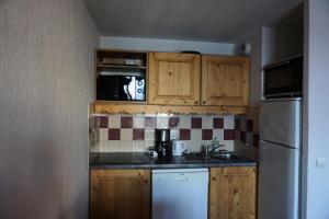 une cuisine avec des armoires en bois et un réfrigérateur blanc dans l'établissement Résidence Cristallines - 2 pièces 4 personnes MAE-4434, à Orcières