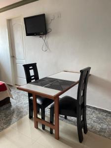 uma mesa de jantar com duas cadeiras e uma televisão na parede em Apartamento tipo estudio em Mérida