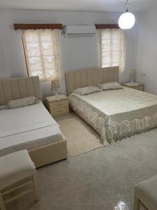 1 Schlafzimmer mit 2 Betten und 2 Fenstern in der Unterkunft N'Eden Hostel in Berat