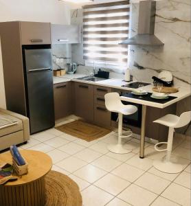 Il comprend une cuisine équipée d'un réfrigérateur, d'une table et de chaises. dans l'établissement Cozy flat with garden, à Tinos