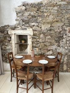 a wooden table with chairs and a stone wall at Gustave charmant appartement en cœur de ville à 20 mètres de la mer in Les Sables-dʼOlonne +4 photos