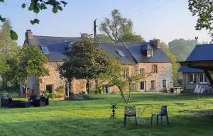 a large brick house with two chairs and a table at L'EAU QUI DORT - Chambres et Tables d'hôtes in Pleslin-Trigavou