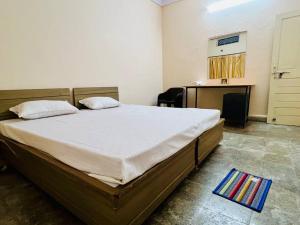 a bedroom with a large bed in a room with a desk at Avanti ONE 2BHK 3KM from Mahakal in Ujjain +5 photos