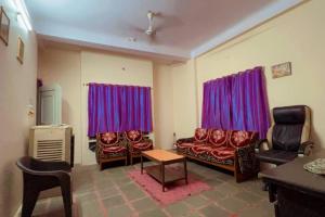 a living room with red chairs and purple curtains at Avanti ONE 2BHK 3KM from Mahakal in Ujjain