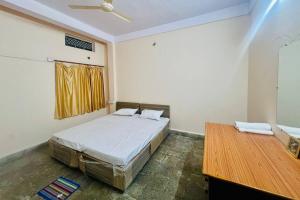 a bedroom with a bed and a wooden table at Avanti ONE 2BHK 3KM from Mahakal in Ujjain