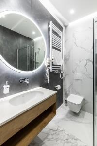 a bathroom with a sink and a toilet and a mirror at SQUARE APARTMENTS GDYNIA in Gdynia
