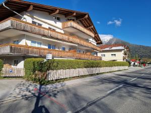 a building with a fence next to a street at Appartement Bergsee SUN - direkt am See - Sonnenbalkon in Seefeld in Tirol