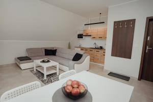 a living room with a couch and a table with a bowl of apples at Apartamenty Kaszuba in Chmielno