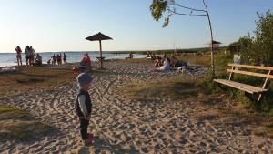 młody chłopiec stojący na plaży z ludźmi w obiekcie Садиба For Rest w mieście Świtaź