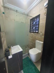 baño con aseo y lavabo y ventana en Queen B Palace en Tema