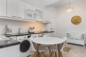 a white kitchen with a white table and chairs at Alpha & Omega Apartments in Karpathos