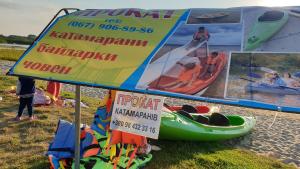 ein Schild am Strand mit einem Kajak und Plakaten in der Unterkunft Садиба For Rest in Switjas