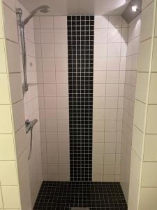 Łazienka z prysznicem wyłożona jest czarno-białymi kafelkami. w obiekcie Lägenhet Gränna w mieście Gränna
