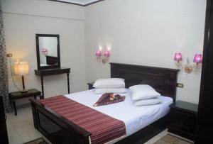 アレクサンドリアにあるNew Siesta Hotel & Resortのベッドルーム1室(白いシーツと鏡付きのベッド1台付)