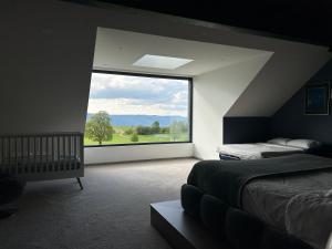 - une chambre avec un lit et une grande fenêtre dans l'établissement Villa de montagne avec piscine intérieure chauffée, à Bellefosse