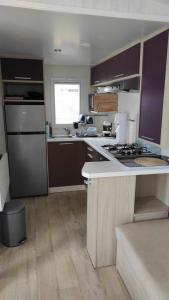 a kitchen with purple cabinets and a stove top oven at Mobile home 4 personnes - La Cotinière - Ile d'Oléron in La Cotinière