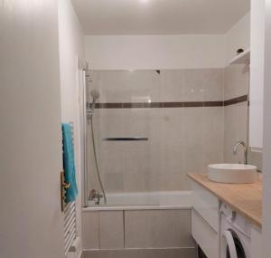 een witte badkamer met een wastafel en een douche bij Cosy Flat - Stade de France in Saint-Denis
