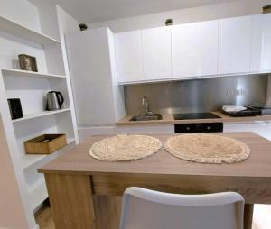 een keuken met witte kasten en een tafel met 2 stoelen bij Cosy Flat - Stade de France in Saint-Denis