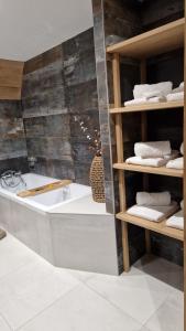 Camera con vasca da bagno e scaffali con asciugamani. di La ferme de Jouane a Besse-et-Saint-Anastaise