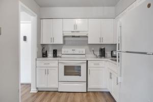 a white kitchen with white cabinets and an oven at Luxury On A Budget! Spacious Retreat Awaits in Wilmington