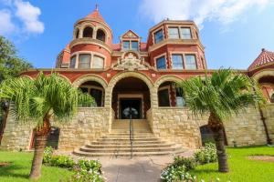 a large red building with palm trees in front of it at Restored Historic Loft - 3 mins to the beach in Galveston