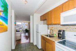 a kitchen with a sink and a white refrigerator at Ilikai Marina 1383 City View Studio in Honolulu