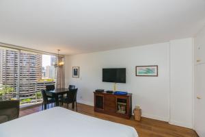 a bedroom with a bed and a tv and a table at Ilikai Marina 1383 City View Studio in Honolulu