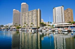 a group of boats docked in a marina with buildings at Ilikai Marina 1383 City View Studio in Honolulu