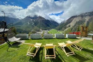 una mesa y sillas en la parte superior de un campo con montañas en Hotel Belvedere, en Cogne