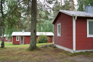 a red house with a tree in front of it at Trehörningsjö camping & stugor in Norrfors