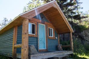 a tiny house with a blue door on a porch at Auberge Festive Sea Shack in Sainte-Anne-des-Monts