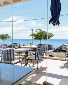 a patio with tables and chairs and the ocean at Aegean Blue Beach Hotel in Nea Kalikratia