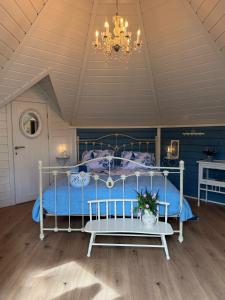 a bedroom with a bed with blue sheets and a chandelier at B&B Cosy Garden in Alblasserdam