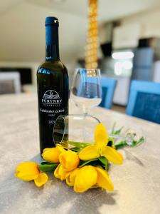 una botella de vino y flores amarillas en una mesa en Elements Lednice, en Lednice