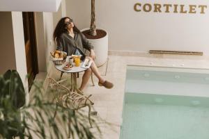 a woman sitting at a table with a bowl of fruit at Cortiletto Timeless Suites in Rethymno