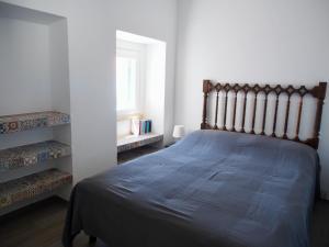 - une chambre avec un lit doté d'une couette bleue et d'une fenêtre dans l'établissement Casal Regina, à Sesimbra