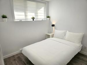 białe łóżko w białym pokoju z oknem w obiekcie Le 4 Saisons 4 w mieście Beaupré