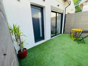 a patio with green grass and a table and chairs at Studio cosy avec mezzanine in Salon-de-Provence