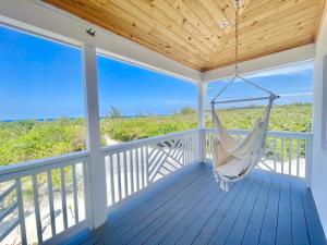 a hammock on a porch with a view of the ocean at The Better Life home in Governorʼs Harbour