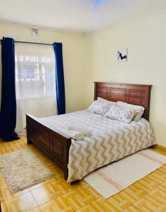 a bedroom with a large bed with blue curtains at Apartment cosy in Narok