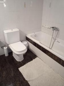 y baño blanco con aseo y bañera. en Traditional Apartment in Volos, en Volos