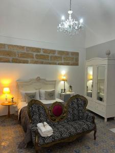 a bedroom with a bed and a couch and a chandelier at Le Alcove in Cinisi