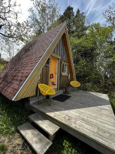 Cabaña pequeña con 2 sillas amarillas en una terraza en Auberge Festive Sea Shack en Sainte-Anne-des-Monts