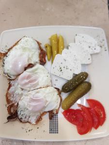 a plate of breakfast food with eggs and pickles at Apartman in Vogošća