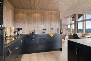 a kitchen with black cabinets and wooden walls at Hytte med fjellutsikt til nydelig natur in Sogndal +19 photos