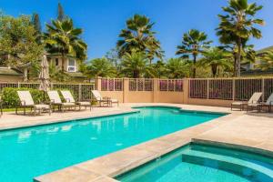 a swimming pool with chairs and a fence and palm trees at Stunning 3br 3ba Corner Unit Villa of Kamalii, AC, Pool, Hot Tub Unit 23 in Princeville