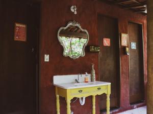 La salle de bains est pourvue d'un lavabo jaune et d'un miroir. dans l'établissement Hospedagem Donalu - Vale do Capão, à Palmeiras