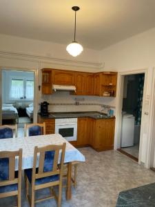 a kitchen with wooden cabinets and a table with chairs at Kiskatona Vendégház in Balatonkenese