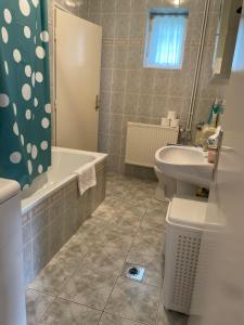 a bathroom with a sink and a tub and a toilet at Kiskatona Vendégház in Balatonkenese
